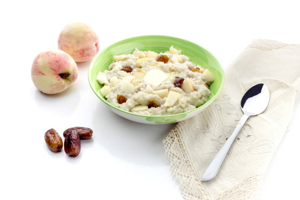 Oatmeal in a plate with pieces of peach and dates fruit close-up on a white background