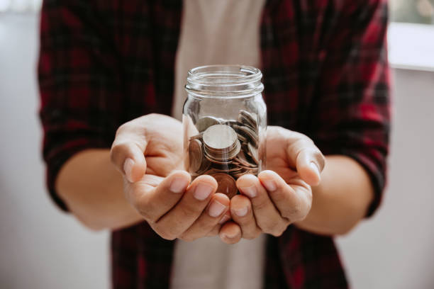 istock Young man hold coins in jar glass. 1386255335