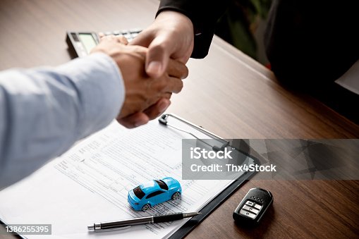 istock Handshake of two young man after deal to make a successful car offer at workshop. 1386255395