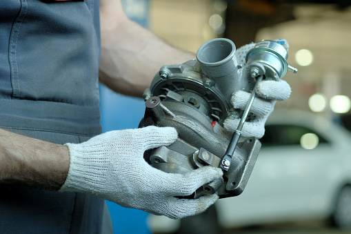 A new turbocharger is in the hands of an auto mechanic. Inspection of the spare part for compliance and integrity.