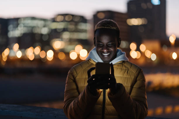 istock Young happy african man using cell phone in the city at night 1386261140