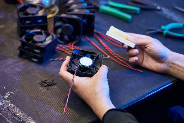 istock A master technologist makes fans for a computer cooling system. Computer Fan Parts lie on the table 1386266530
