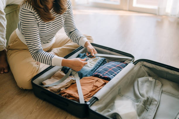Asian woman packing suitcase at home for journey in vacation day. stock photo