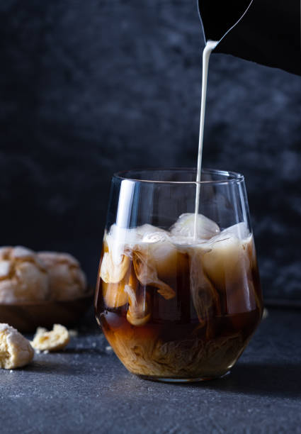 istock Cream from a black milk jug is poured into iced coffee 1386271965