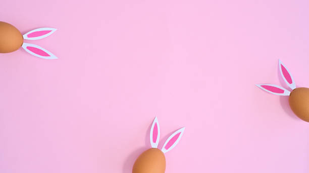 istock Creative copy space backround with natural eggs with rabbit ears on pastel pink theme. Flat lay Easter concept 1386276411