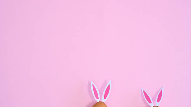 istock Two natural eggs with rabbit ears peek on pastel pink background with copy space. Easter flat lay minimal 1386276662