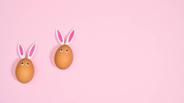 istock Two natural eggs with bunny ears and eyes on pastel pink background. Flat lay copy space Easter concept 1386276679