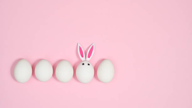 istock Creative composition with white eggs and one with rabbit ears on pastel pink background. FLat lay creative Easter copy space. 1386276820