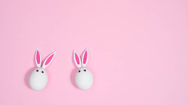 istock White eggs with rabbit ears on pastel pink background. Flat lay minimal creative concept. Easter holidays 1386276895