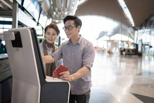 couple chinois asiatique vérifiant par machine d’enregistrement automatique à l’aéroport. - matériel denregistrement photos et images de collection