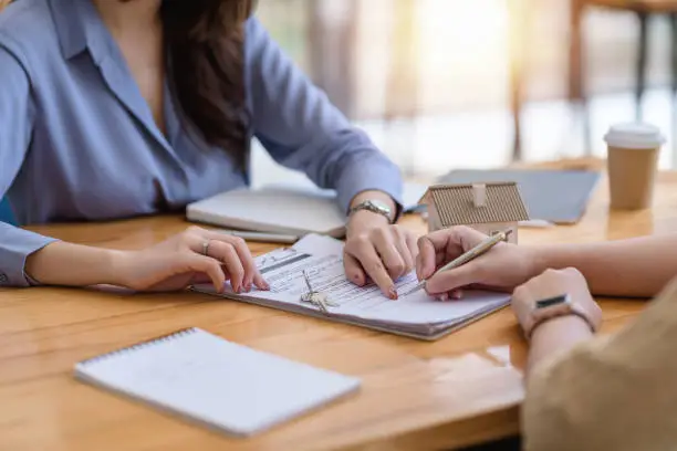 Woman real estate agent talking to client in office. Signing home purchase contract with customer.