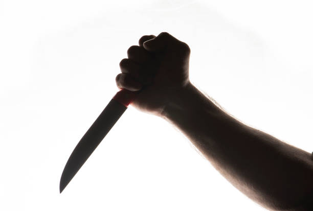 istock Man hand silhouette on the white background holding  the knife. 1386286280