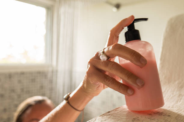 woman takes shower and uses pink conditioner - shampoo imagens e fotografias de stock