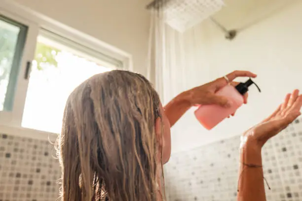 Photo of Woman takes shower and uses pink conditioner