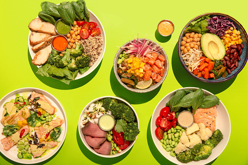 Many Hawaiian dieting poke bowls with chicken, quinoa, broccoli, chickpeas, tomato and spinach. Top view, overhead, flat lay.