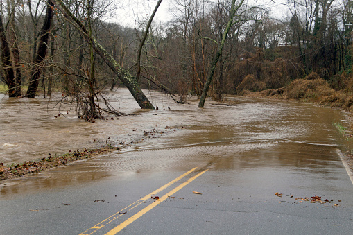 A river floods onto a road making it hazardous and impassable