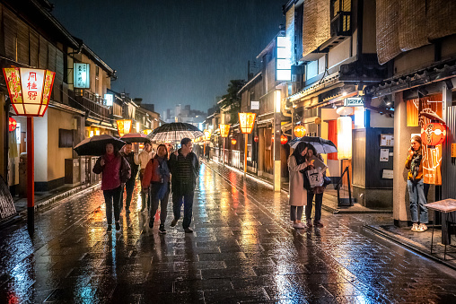 march 30, 2019 - Kyoto, Japan: raining night in the street in Gion district at night with people and illuminated restaurant buildings
