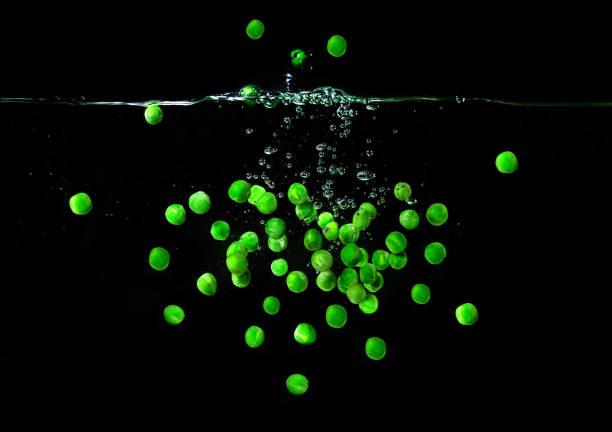 istock green peas falling in the boiling water on dark background. Underwater view. Cooking, vegetarian, cooking at home concept 1386307810