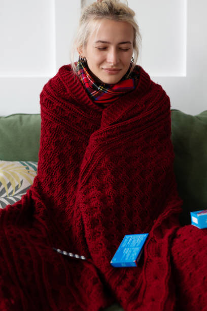 istock A woman keeps warm by wrapping herself in a blanket while sitting at home 1386308357