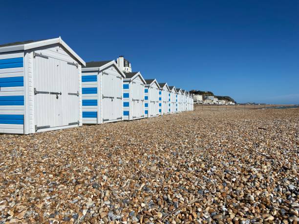 Hastings, East Sussex, UK -03.15.2022: Hastings seafront beach huts on summer day beautiful blue white striped huts on pebble beach Hastings, East Sussex, UK -03.15.2022: Hastings seafront beach huts on summer day beautiful blue white striped huts on pebble beach east sussex stock pictures, royalty-free photos & images