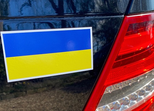 Close up yellow and blue Ukrainian flag sticker on the rear on bumper on black car