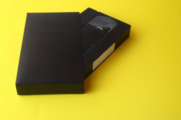 istock Black VHS video tape cassette with blank label isolated on yellow background 1386319145