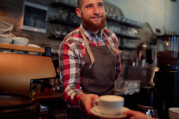 istock A smiling waiter works with customers in a coffee shop. 1386334297