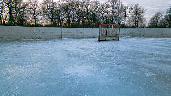 A bright red hockey net on a outdoors ice rink