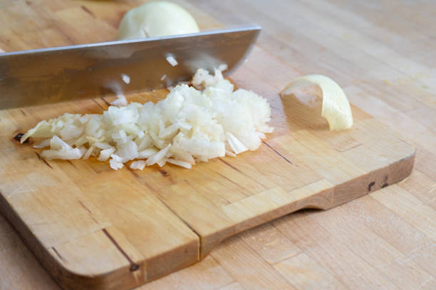 istock Large kitchen knife cuts onions into small cubes on a wooden cutting board, copy space, selected focus 1386335390