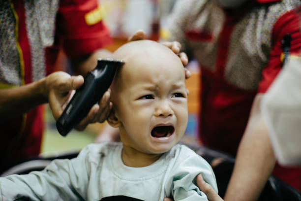 Crying asian  baby getting hair cut