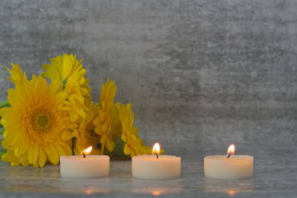 Yellow flowers and burning tea light candles - selective focus stock photo