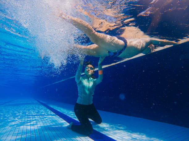 istock underwater Asian Chinese female trainer teaching coaching senior man learning swimming with leg movement in the swimming pool 1386348581