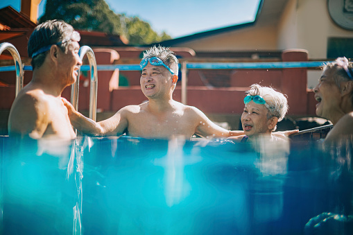 Asian Chinese Senior friends talking bonding in swimming pool during weekend morning