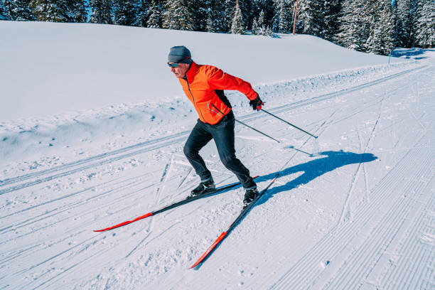 tiro grande angular de um esquiador de skate cross-country esquiando em uma formação v2 ao longo de uma trilha preparada em um dia claro e ensolarado na floresta nacional grand mesa no colorado - colorado skiing usa color image - fotografias e filmes do acervo