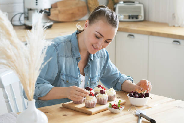 istock Young woman decorates cupcakes with berries 1386368806