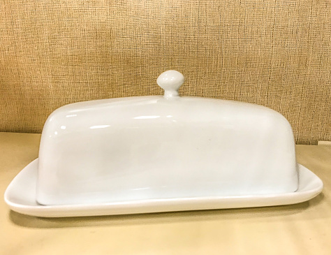 A white ceramic milk butter dish sits on display.