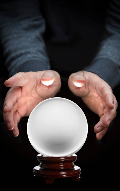 istock Crystal ball fortune teller with hands hovering over with wood base on black background 1386382423
