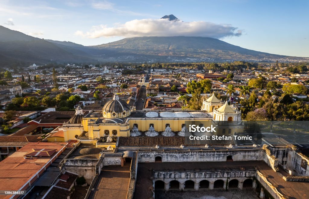 Convent and Church of La Merced in downtown Antigua Guatemala with a view of the Agua Volcano Drone view of the convent and Church of La Merced in downtown Antigua Guatemala with a view of the inactive Agua Volcano on a sunny bright morning Antigua - Western Guatemala Stock Photo