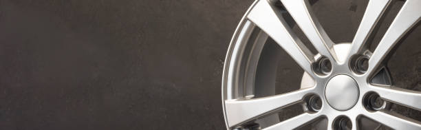 istock new grey alloy wheels on a dark textured black background. car wheel , copy space panorama empty space 1386387101