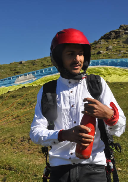 a indian young male tourist opening bottle cap for drink water before taking paragliding flight in the mountain - parachuting open parachute opening imagens e fotografias de stock
