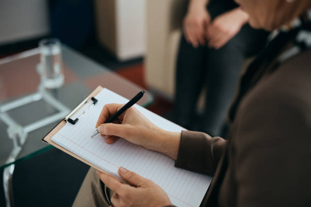 Close-up of mental health professional taking notes during counseling with a patient. Close-up of female psychiatrist writing notes while having therapy session with a patient. personality test stock pictures, royalty-free photos & images