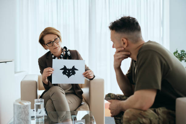 Military man having Rorschach inkblot test  during meeting with psychiatrist. Mature psychiatrist evaluating mental disorder of a soldier with inkblot test during counseling at her office."n"n personality test stock pictures, royalty-free photos & images