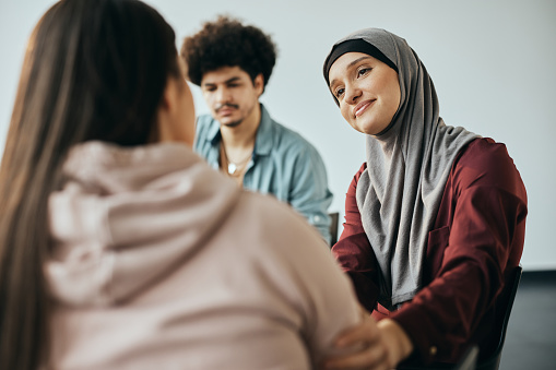 Caring Middle Eastern woman supporting new attender of group therapy to talk about herself during the meeting at mental health center.