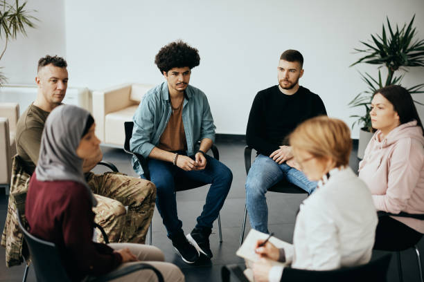 Multiracial people participating in group therapy at mental health center. Multi-ethnic participants on group therapy having meeting with their psychotherapist at community center. group therapy photos stock pictures, royalty-free photos & images