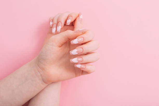 istock female hands with beautiful long nails with  manicure with  heart pattern on pink background 1386402609