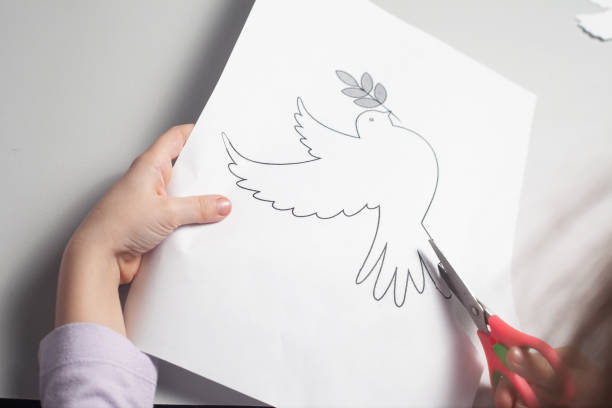 istock Children's hands are carving a crane on a white paper with small scissors 1386404793