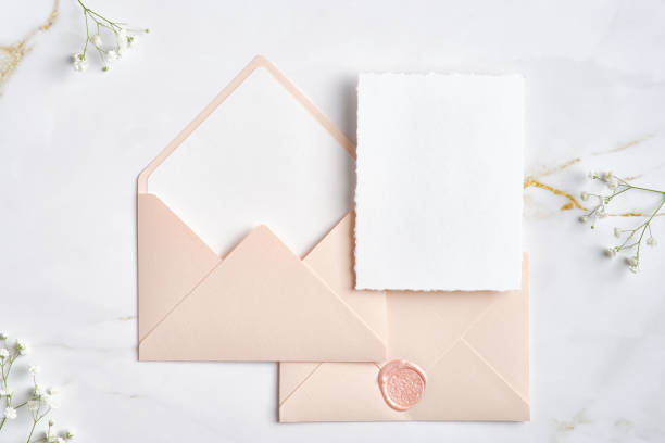 istock Blank white invitation cards with pink envelopes and gypsophila branches on marble table. Wedding stationery set. Flat lay, top view, copy space. 1386404900