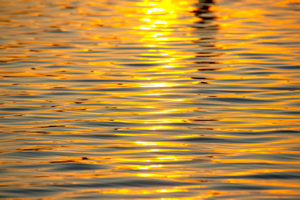 istock Reflection of the setting sun in a wave of water. Natural background texture 1386407970