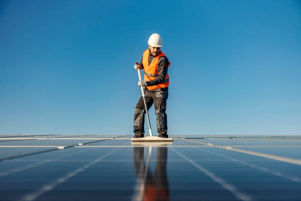 istock A handyman brushing solar panels with broom on the roof. 1386418331