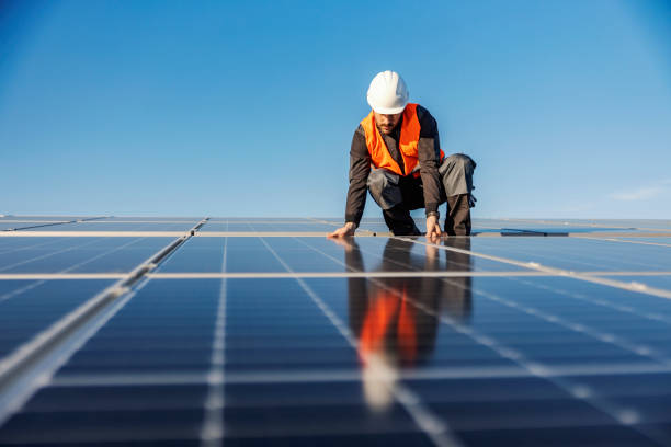 A handyman installing solar panels on the rooftop. A worker installing solar panels on the roof. climate justice photos stock pictures, royalty-free photos & images